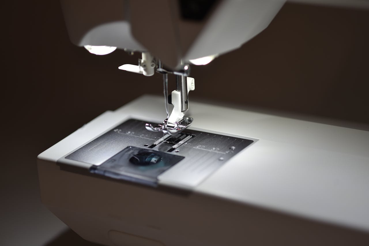 Home Detailed view of a sewing machine's presser foot illuminated by soft lighting.